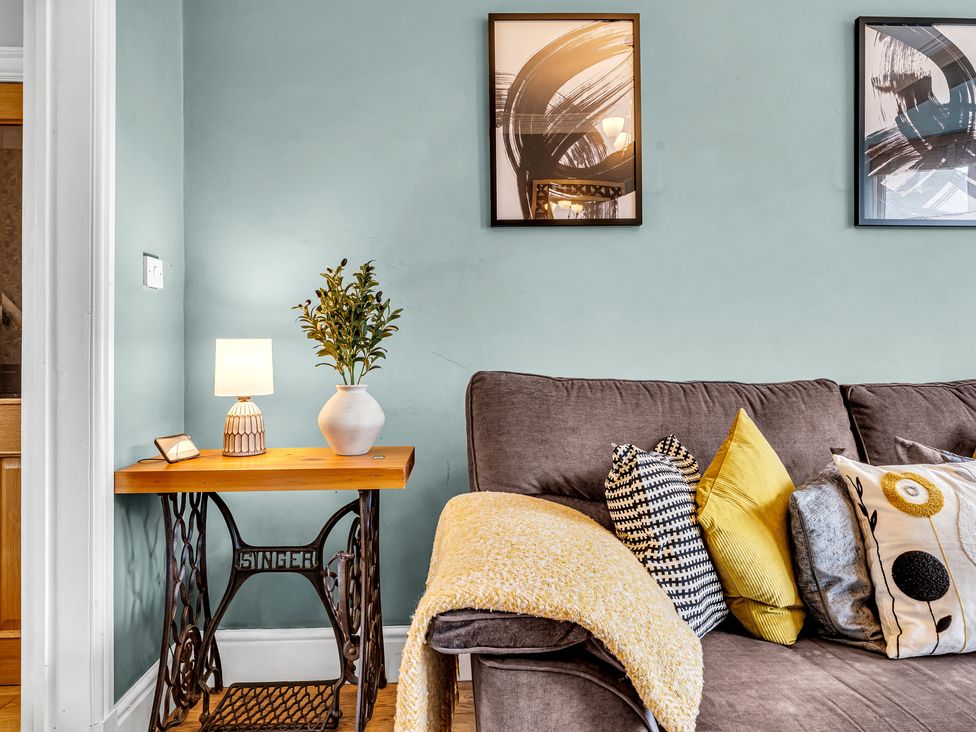A living room with a sofa, lamp, and table at Stoke Townhouse in Stoke-on-Trent