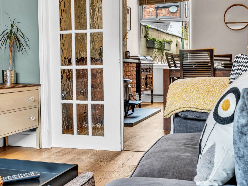 A living room with a chest of drawers and an open glass door at Stoke Townhouse in Stoke-on-Trent