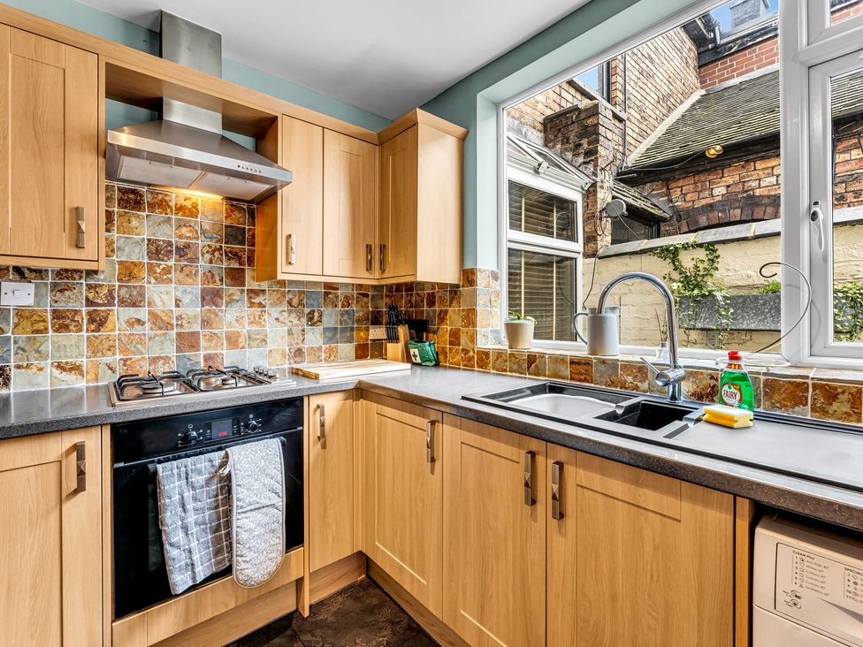A kitchen with cabinets, sink, stove and window at Stoke Townhouse in Stoke-on-Trent