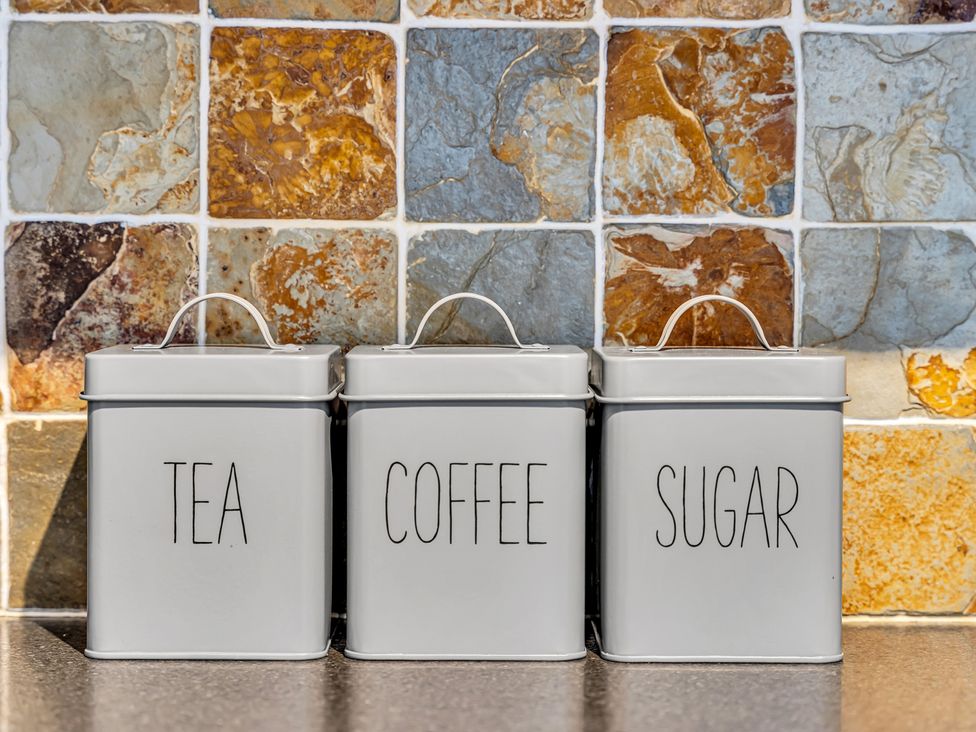 Three storage tins labeled tea, coffee, and sugar in a kitchen at Stoke Townhouse in Stoke-on-Trent