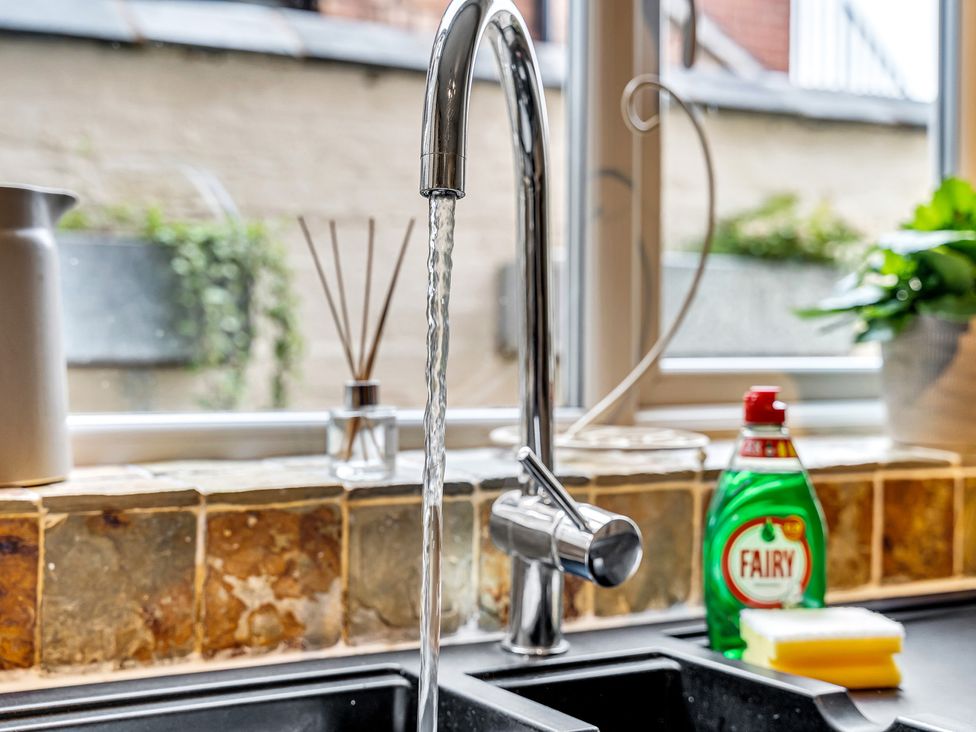 A faucet with water flowing in a kitchen sink at Stoke Townhouse in Stoke-on-Trent