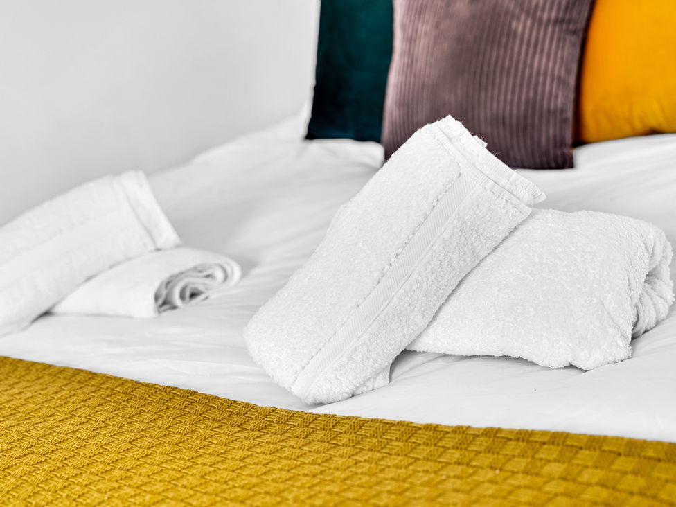 A bed with towels and cushions at Stoke Townhouse in Stoke-on-Trent