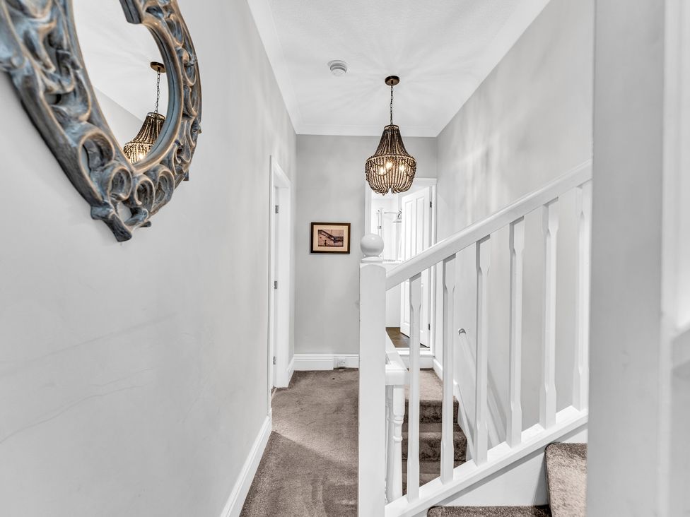 A hallway with a staircase and light fixture at Stoke Townhouse in Stoke-on-Trent