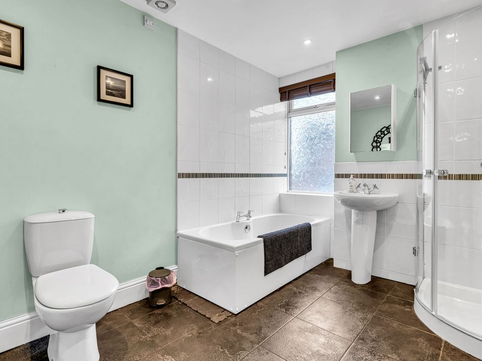 A bathroom with a bathtub, shower, toilet, and sink at Stoke Townhouse in Stoke-on-Trent