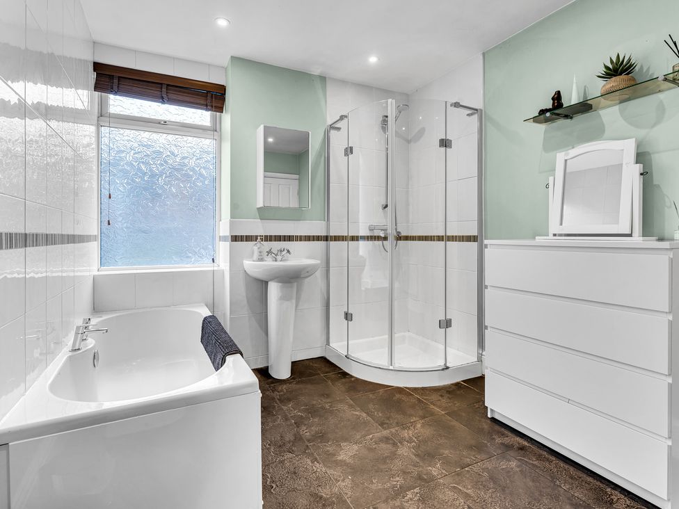 A bathroom featuring a bathtub, shower, sink and storage at Stoke Townhouse in Stoke-on-Trent