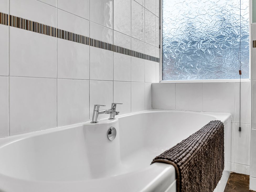 A bathtub with a faucet near a window in Stoke Townhouse Stoke-on-Trent