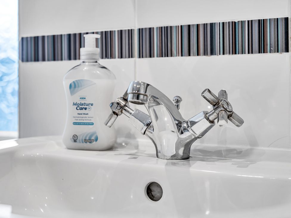 A sink with a tap and hand wash bottle at Stoke Townhouse in Stoke-on-Trent
