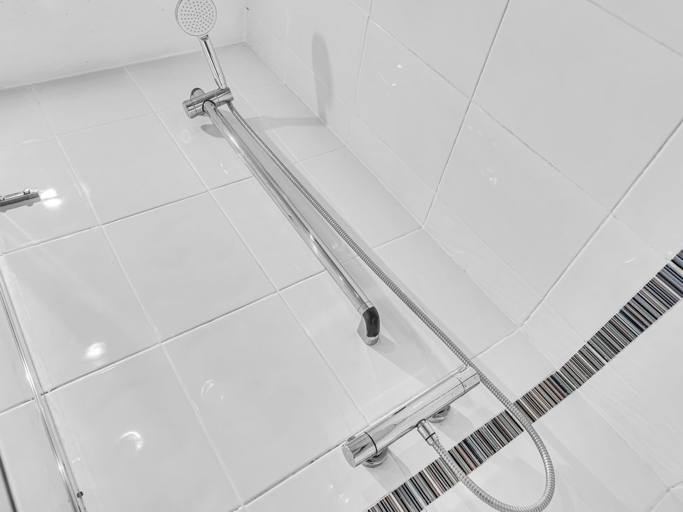A shower area with wall tiles and a handheld shower at Stoke Townhouse in Stoke-on-Trent