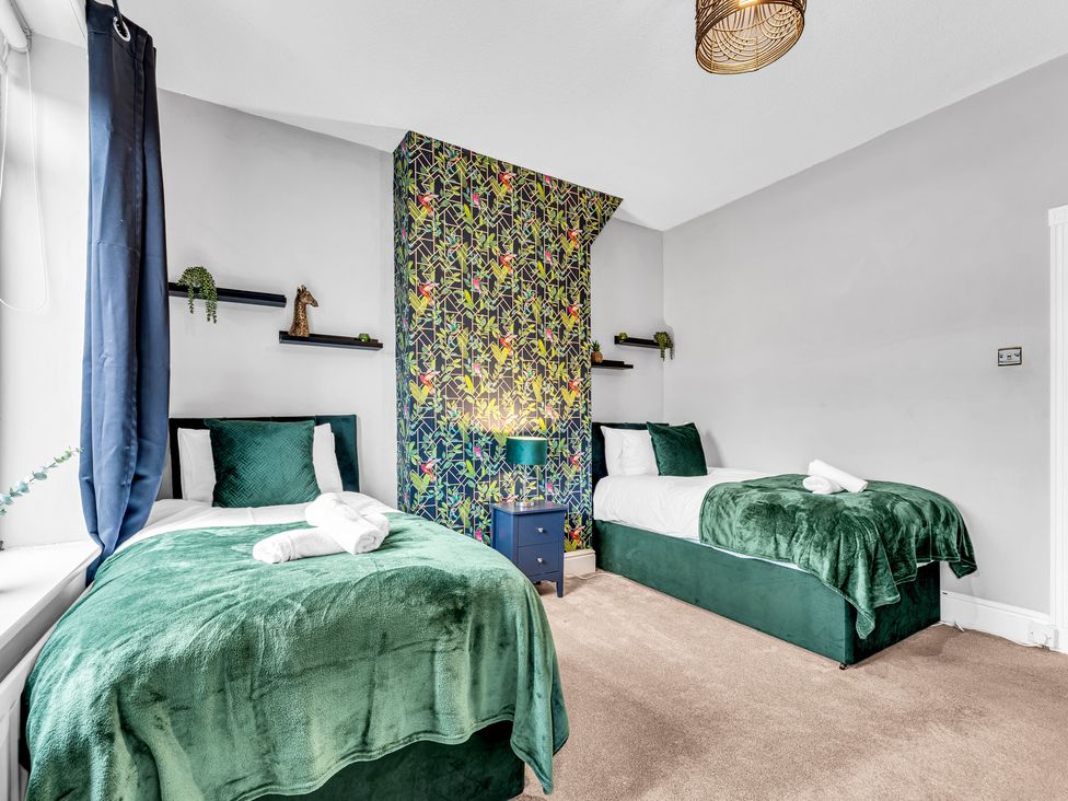 A bedroom with two beds and a bedside table at Stoke Townhouse in Stoke-on-Trent