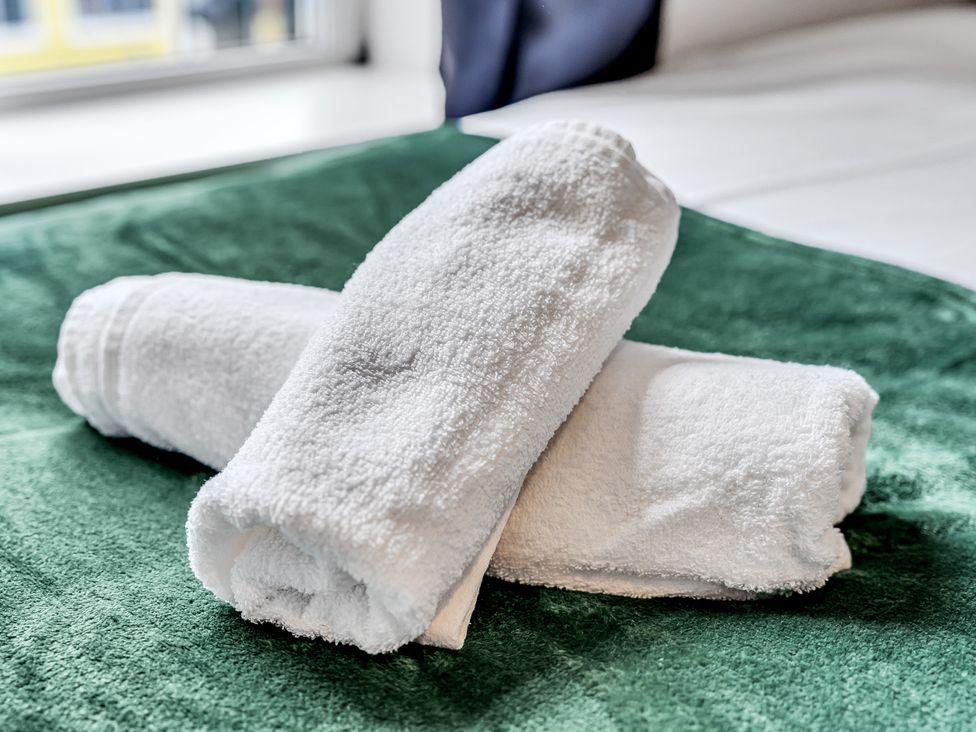 Two rolled towels on a green blanket at Stoke Townhouse in Stoke-on-Trent