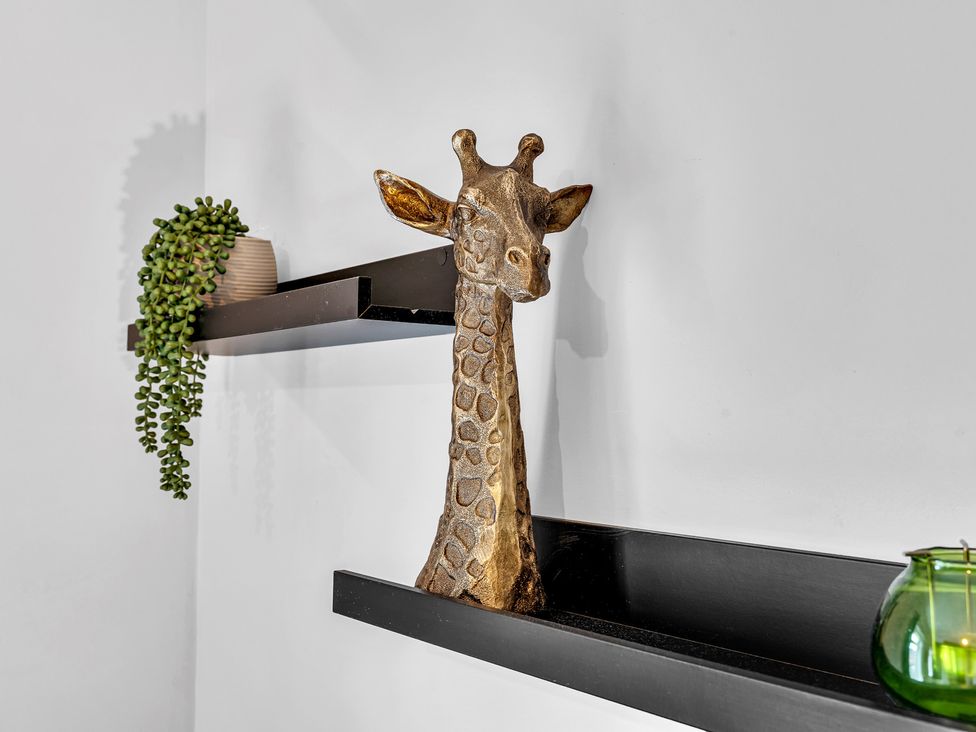 A giraffe sculpture on a shelf with a plant at Stoke Townhouse in Stoke-on-Trent