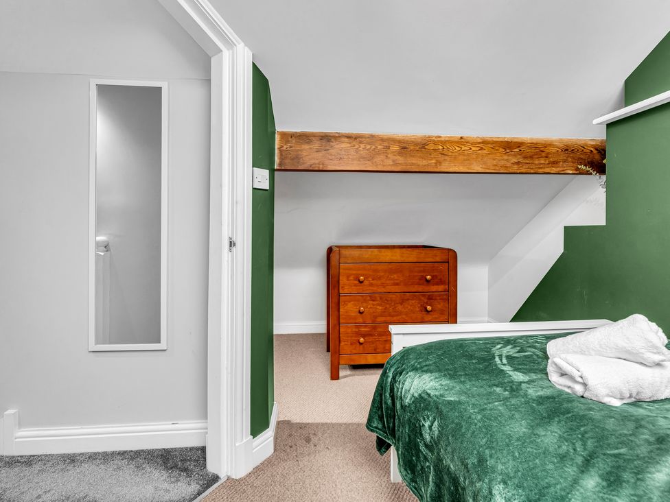 A bedroom with a mirror and a wooden drawer at Stoke Townhouse in Stoke-on-Trent