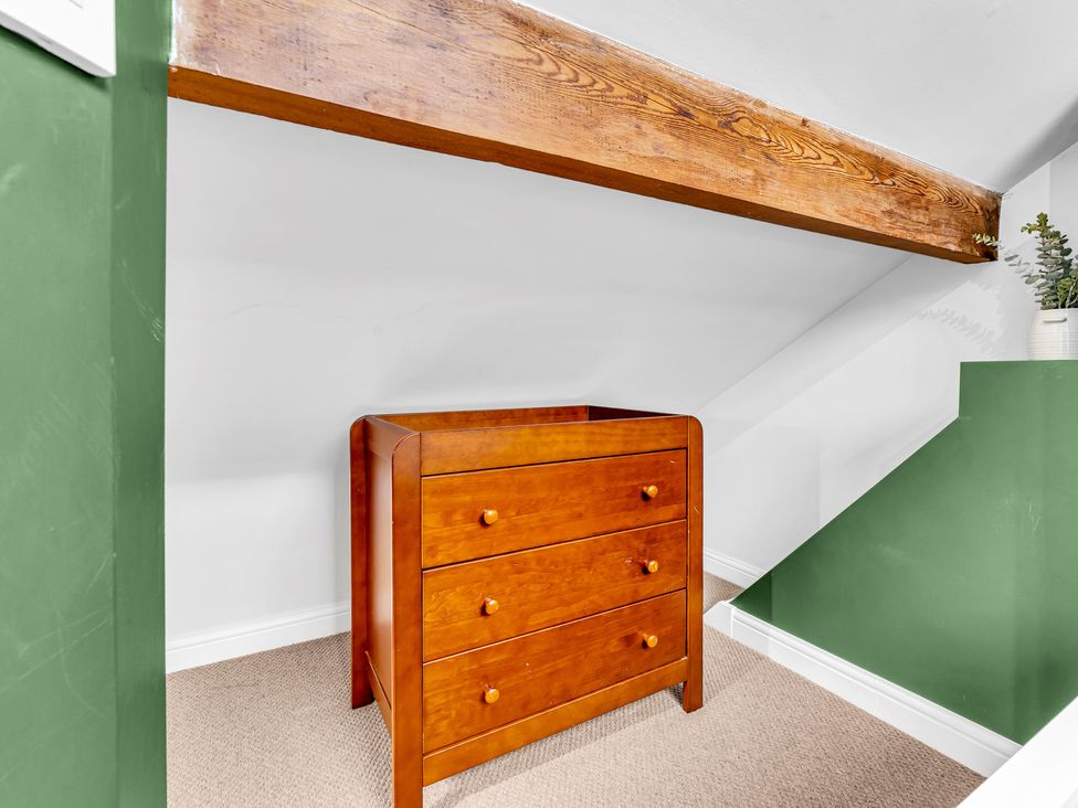 A storage space with a wooden chest of drawers and green wall at Stoke Townhouse in Stoke-on-Trent