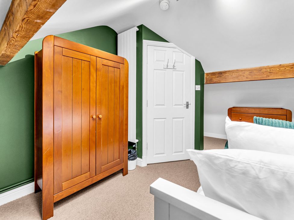A bedroom with a wooden wardrobe and a door at Stoke Townhouse in Stoke-on-Trent