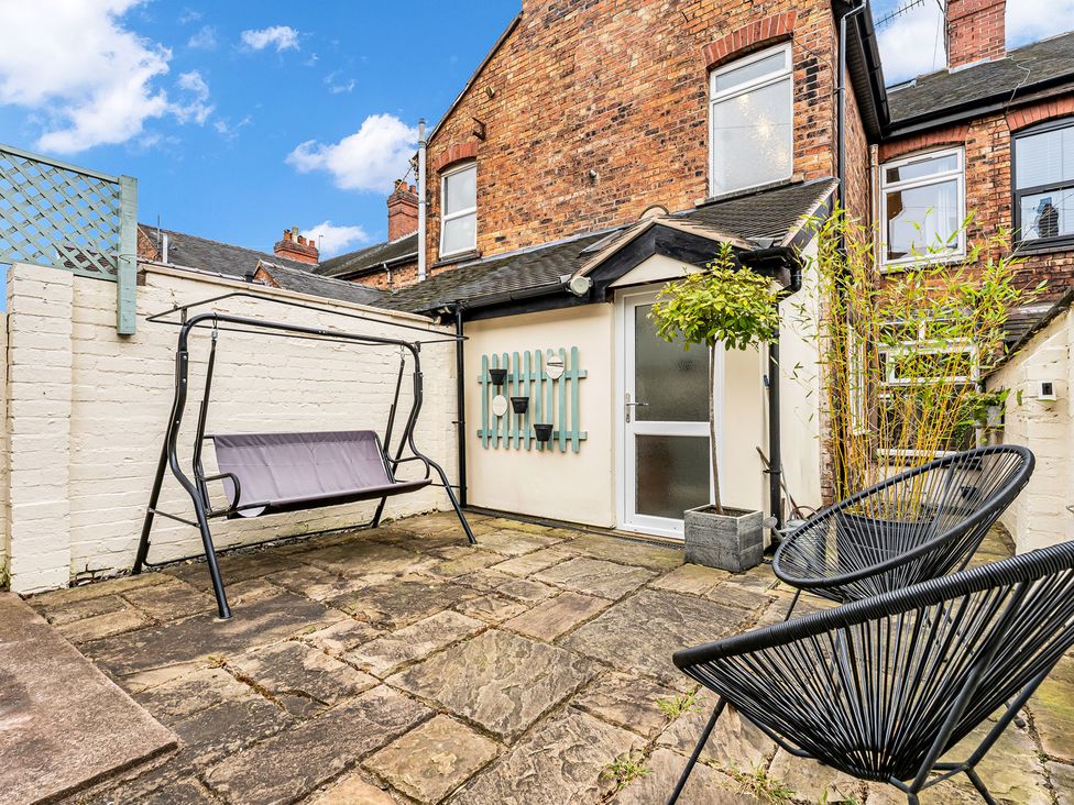 A garden with a swing seat and outdoor chairs at Stoke Townhouse in Stoke-on-Trent