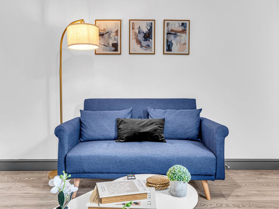 A living room with a blue sofa and floor lamp at Victoria House, Stoke on Trent