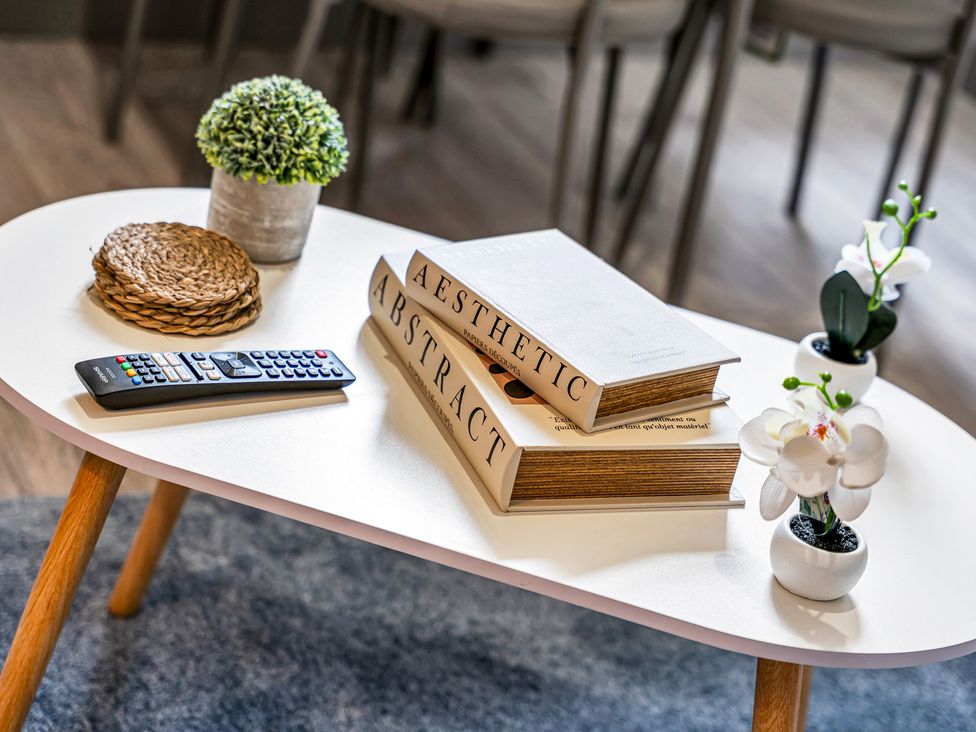 A coffee table with books, a remote, and plants at Victoria House, Stoke on Trent