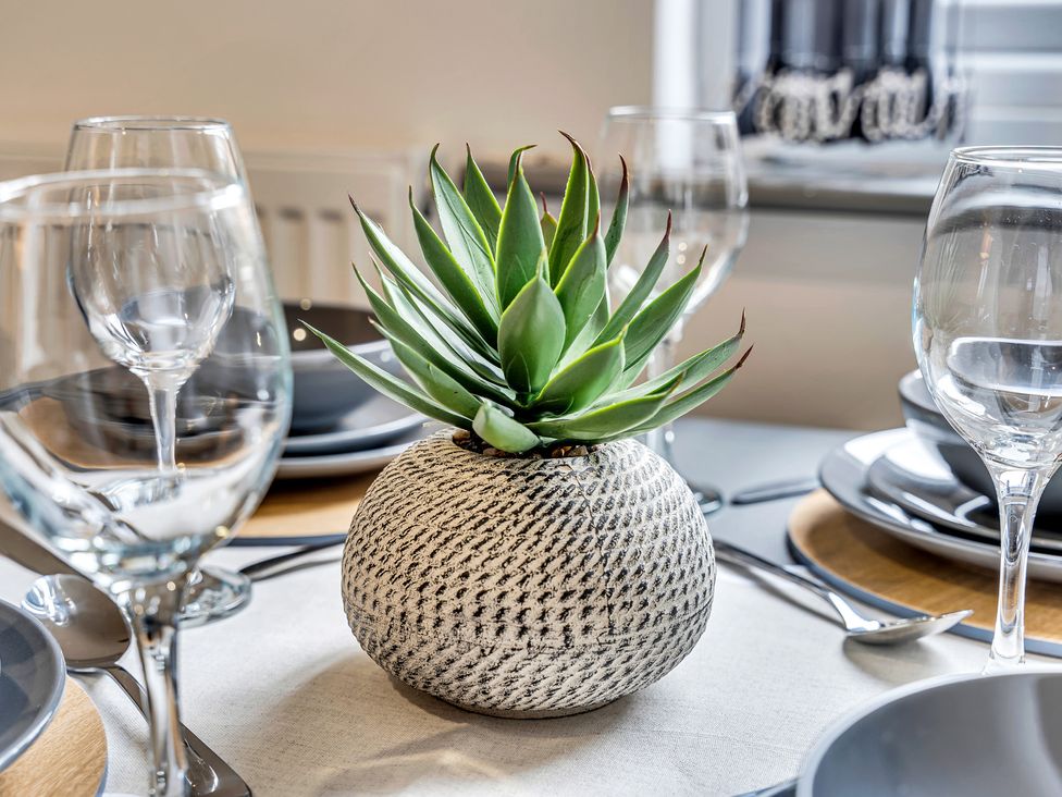 A dining table set with plates and glasses featuring a decorative plant at Victoria House, Stoke on Trent