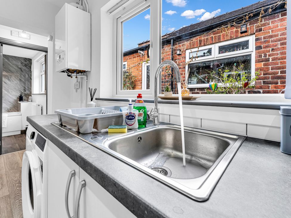 A kitchen with a sink and cleaning supplies at Victoria House, Stoke on Trent