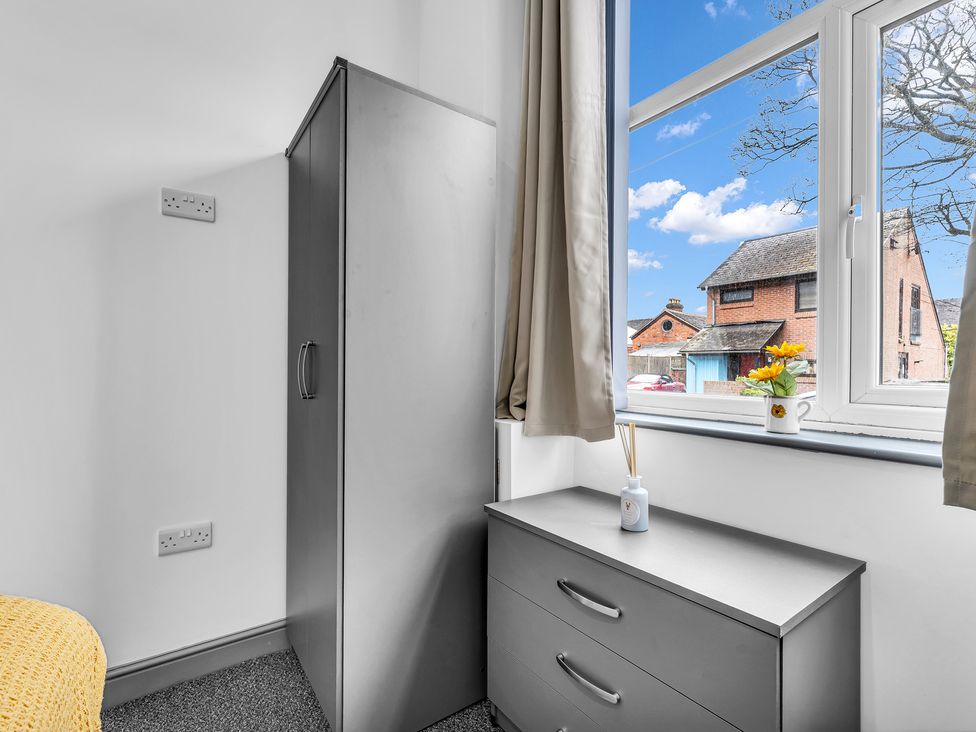 A bedroom with a wardrobe drawer unit and window at Victoria House, Stoke on Trent