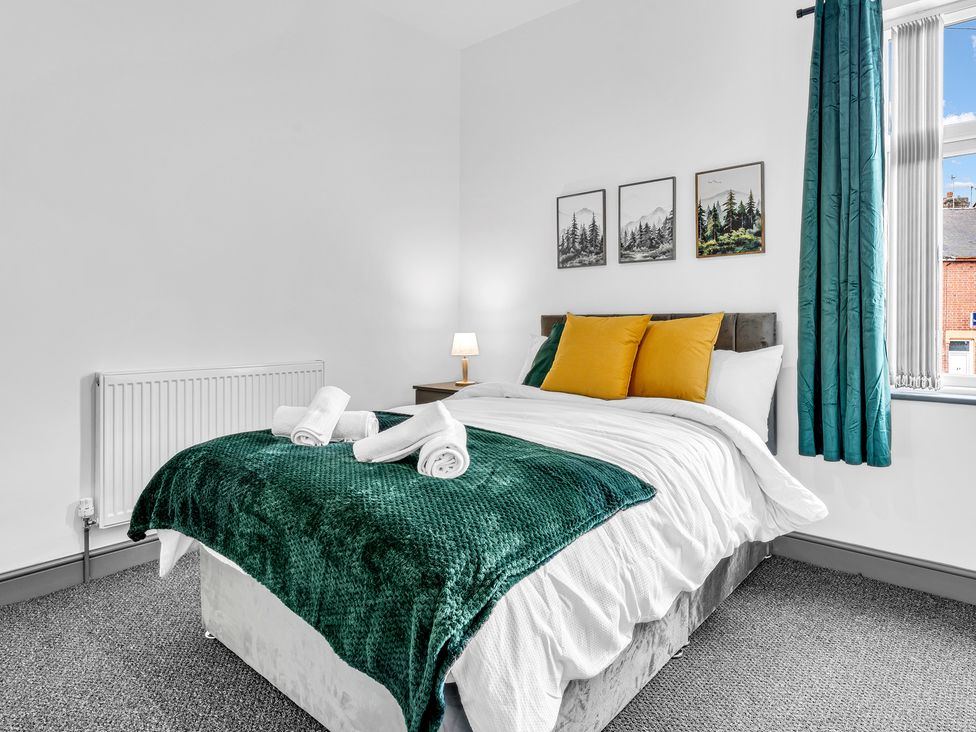 A bedroom with a bed, lamp, and pictures on the wall at Victoria House, Stoke on Trent