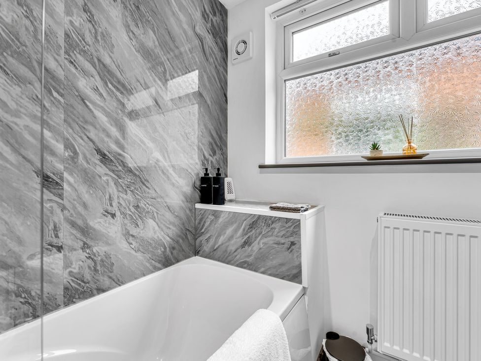 A bathroom with a bathtub and window at Victoria House, Stoke on Trent