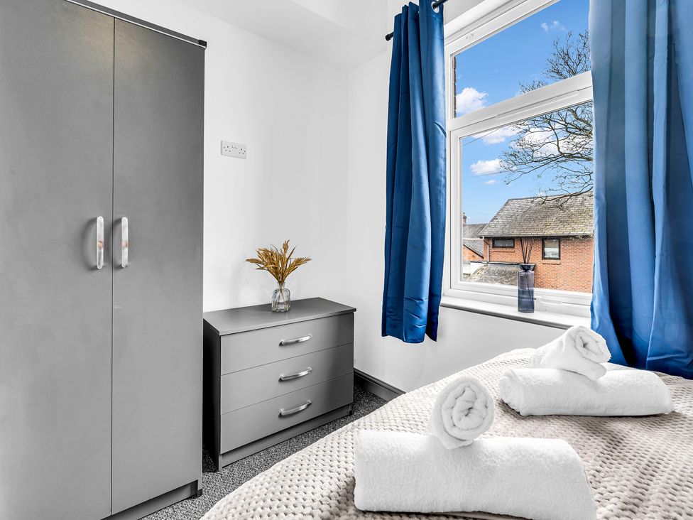 A bedroom with a wardrobe and dresser at Victoria House, Stoke on Trent