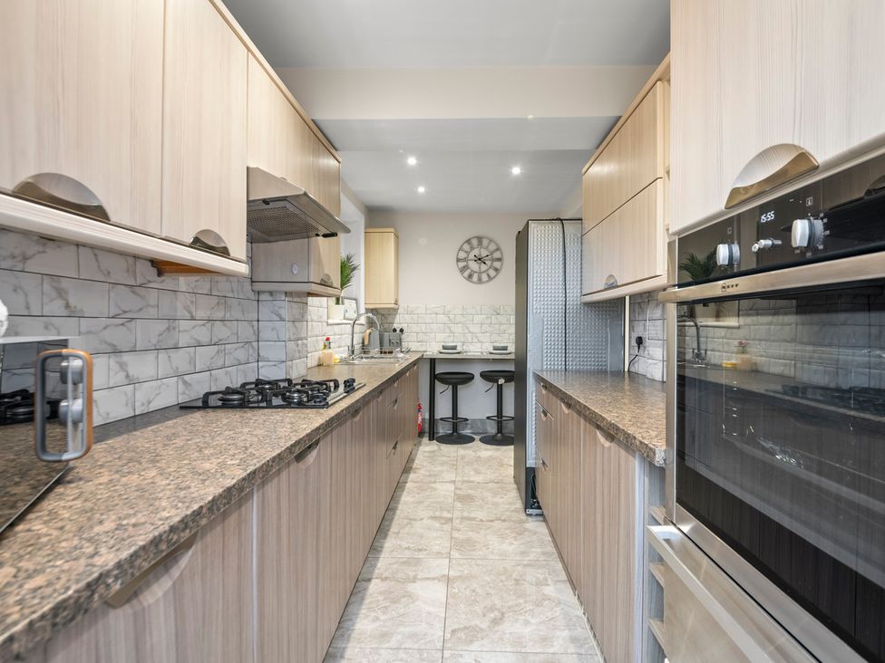 A kitchen with cabinets, gas stove, oven, and bar stools at Oxford City Stay – Cooper House in Oxford