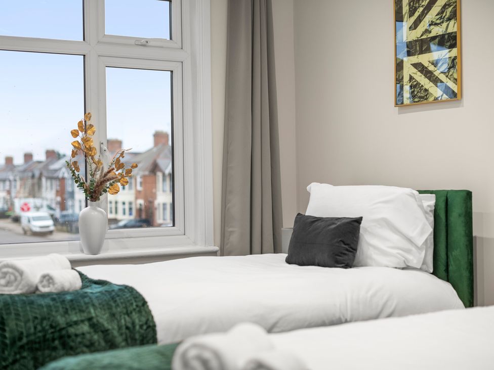 A bedroom with two beds, a window, a vase with flowers at Oxford City Stay – Cooper House, Oxford