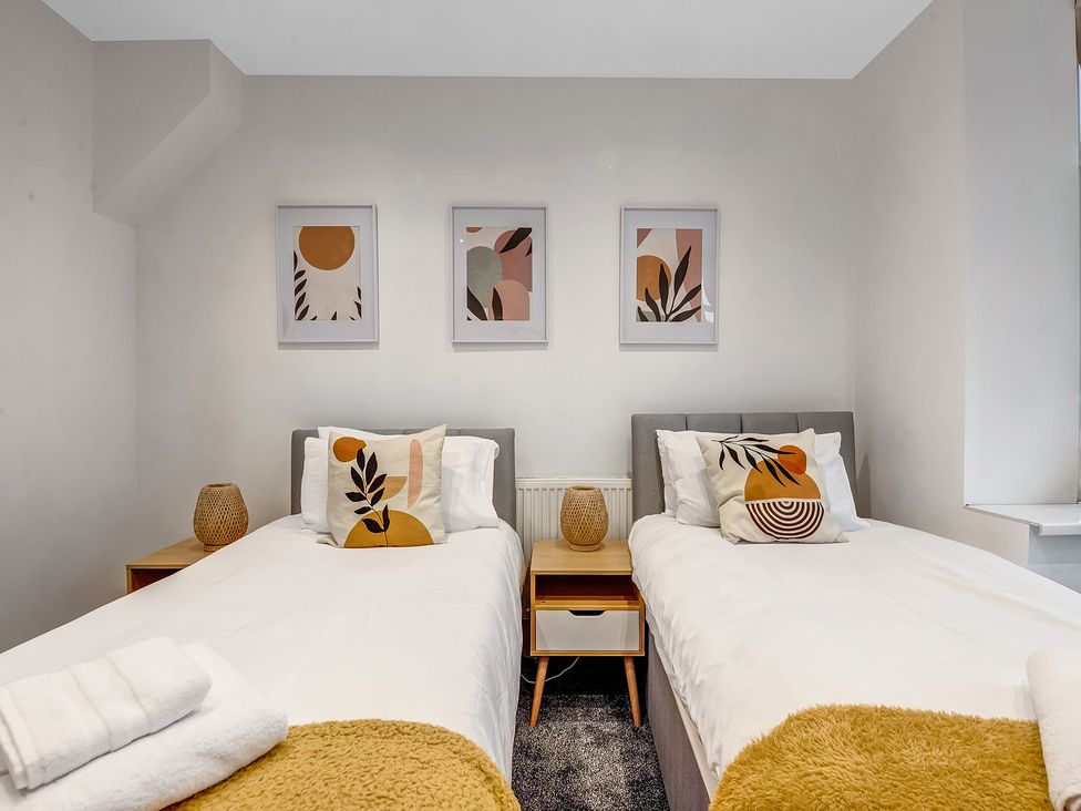 A bedroom with two beds, nightstand, and framed artwork at Oxford City Stay – Cowley House in Oxford