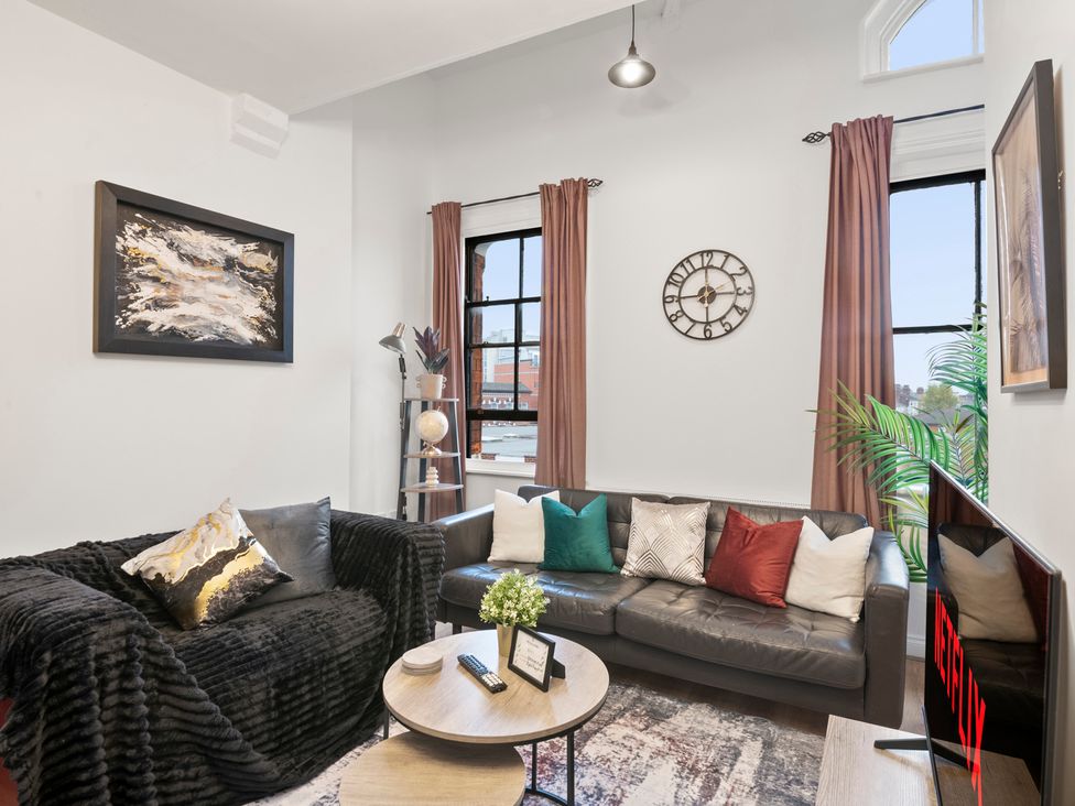 A living room with a sofa, coffee table, and television at The Hallmark Birmingham Flat in Birmingham
