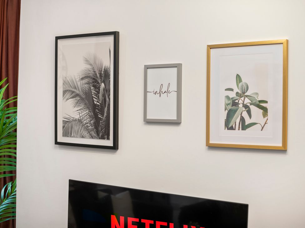 A living room with framed artwork and a television at The Hallmark Birmingham Flat in Birmingham