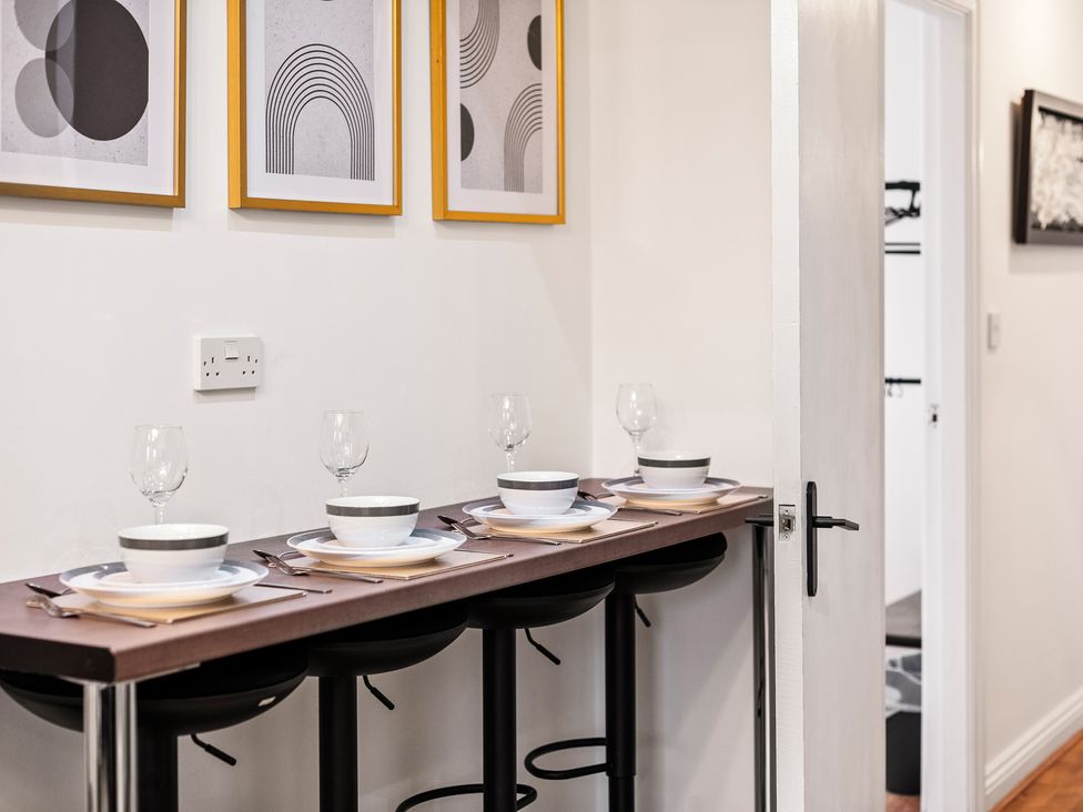 A kitchen with a bar table and stools arranged with plates and glasses at The Hallmark Birmingham Flat Birmingham