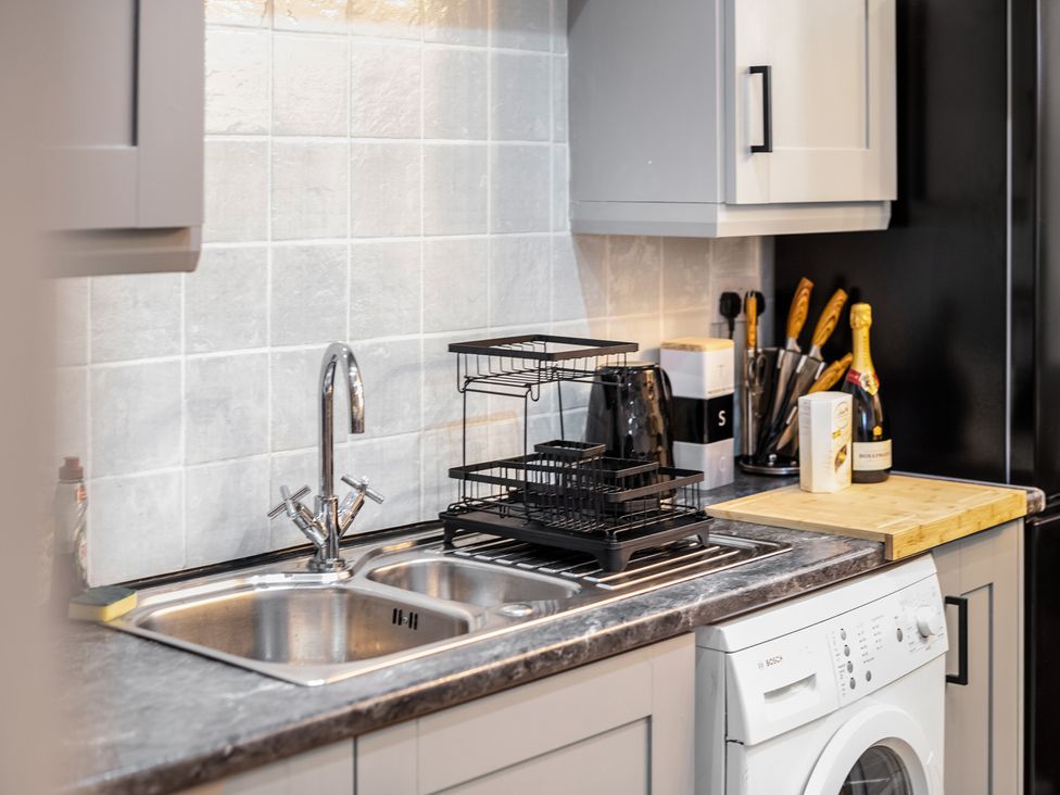 A kitchen with sink, dish rack, and washing machine at The Hallmark Birmingham Flat Birmingham