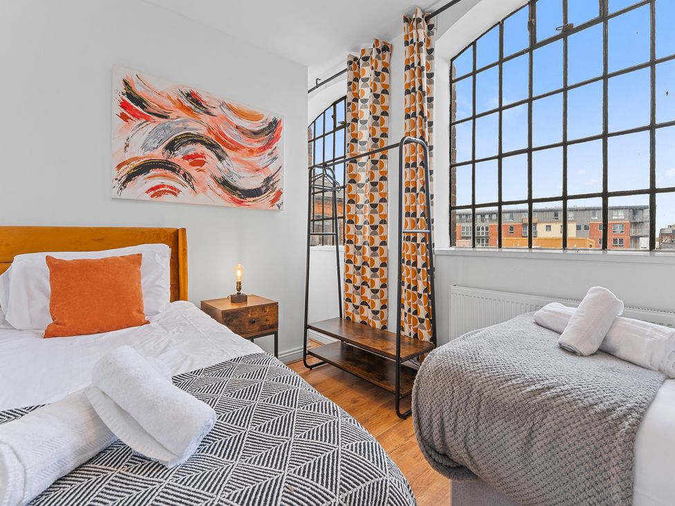 A bedroom with a bed, nightstand, and window at The Hallmark Birmingham Flat Birmingham