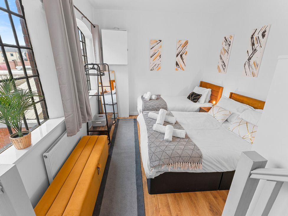 A bedroom with two beds and a bench at The Hallmark Birmingham Flat Birmingham