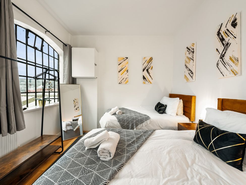 A bedroom with two beds a mirror and wardrobe at The Hallmark Birmingham Flat Birmingham
