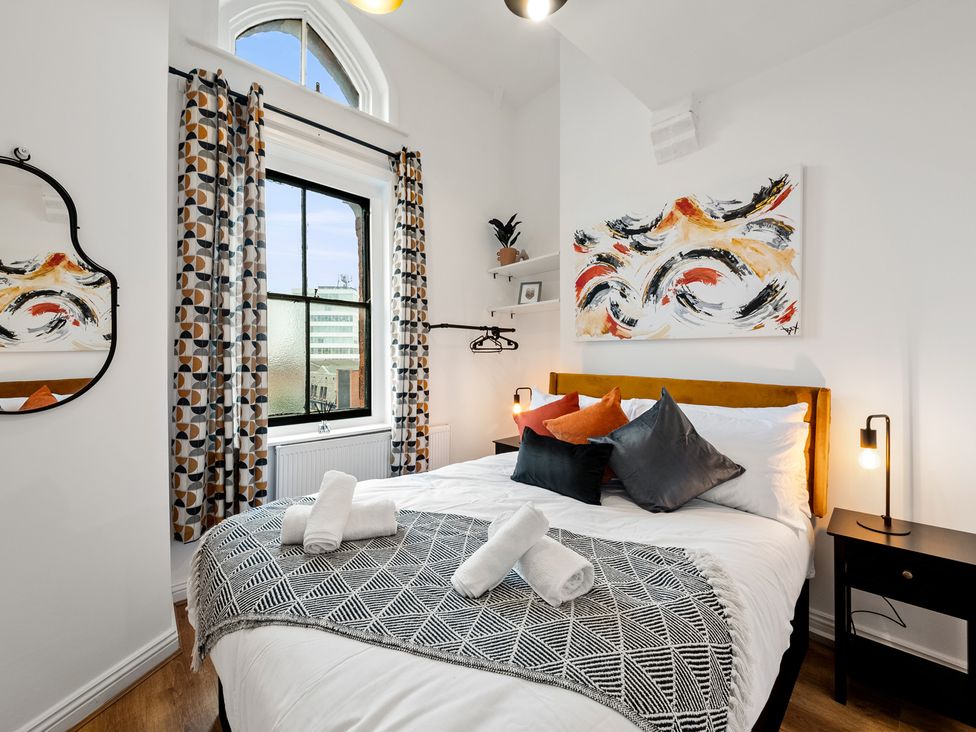 A bedroom with a bed, artwork on the wall, and a window at The Hallmark Birmingham Flat Birmingham