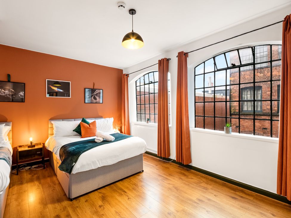 A bedroom with a bed and large windows at The Jewel Box Birmingham City Apartment Birmingham
