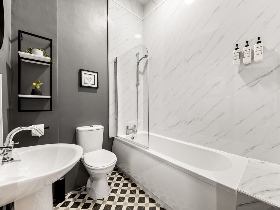 A bathroom with a bathtub, toilet, and sink at The Jewel Box Birmingham City Apartment Birmingham