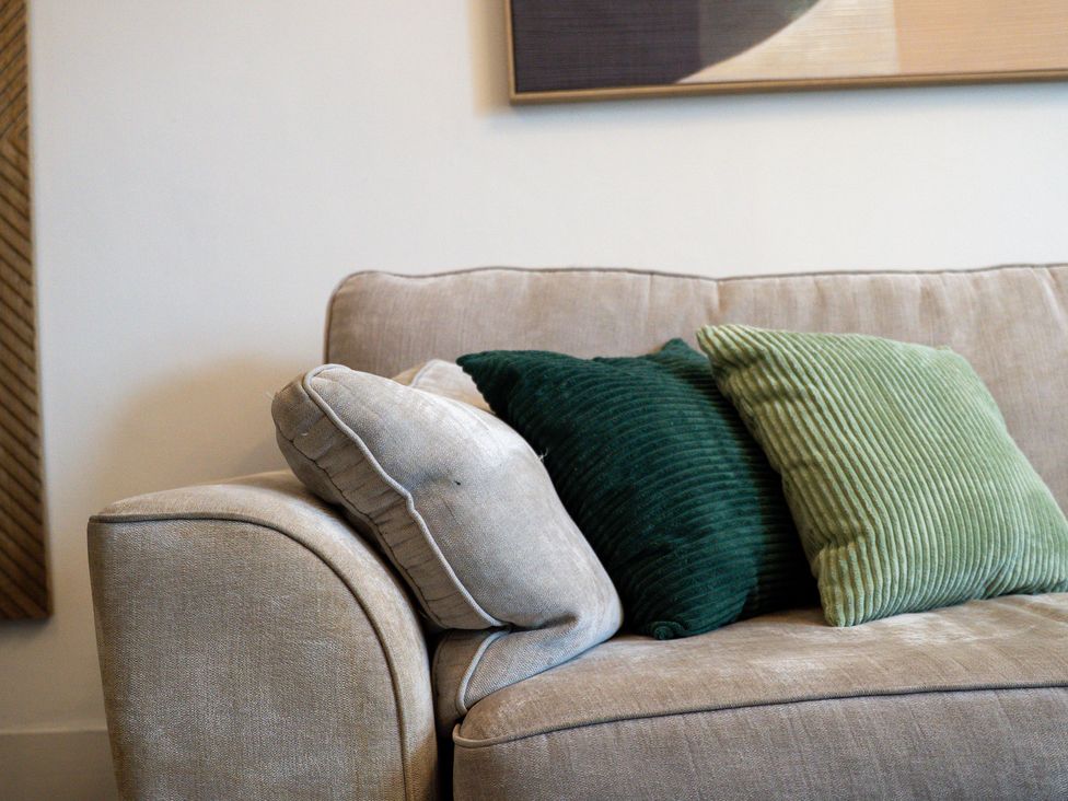 A sofa with green and beige pillows at The Gilder Birmingham City Apartment in Birmingham