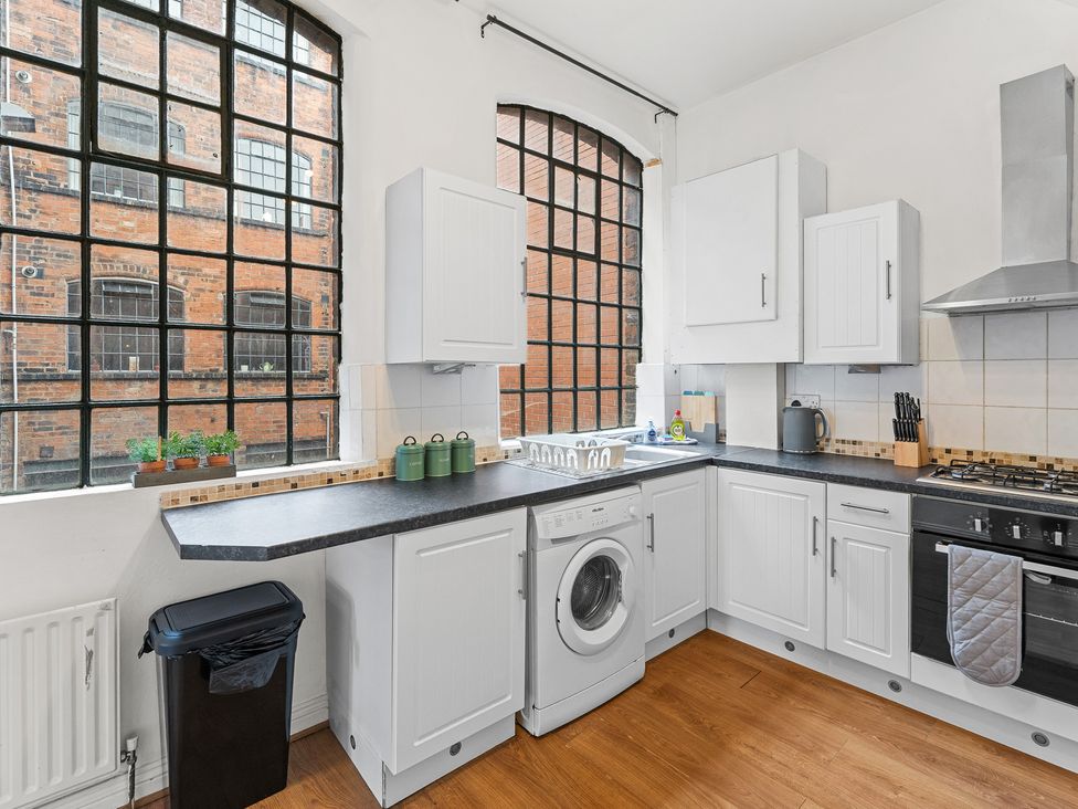 A kitchen with a washing machine and windows at The Gilder Birmingham City Apartment Birmingham