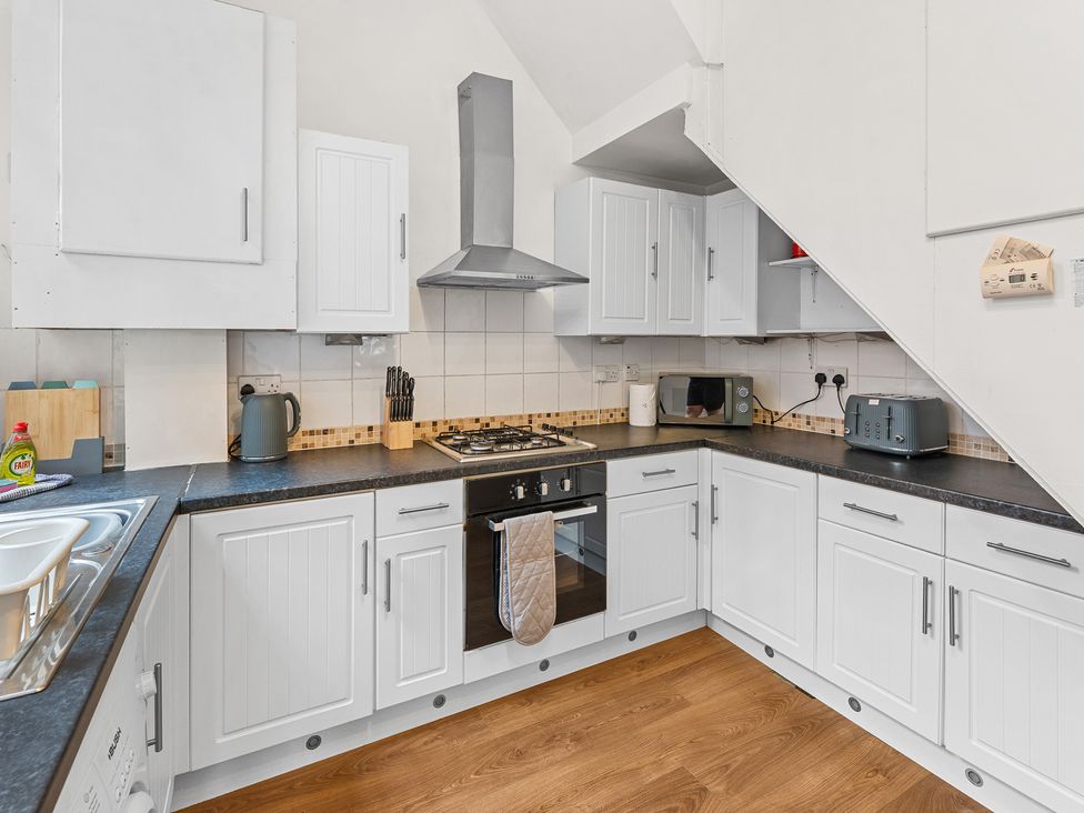 A kitchen with cabinets, stove, sink, microwave and toaster at The Gilder Birmingham City Apartment in Birmingham