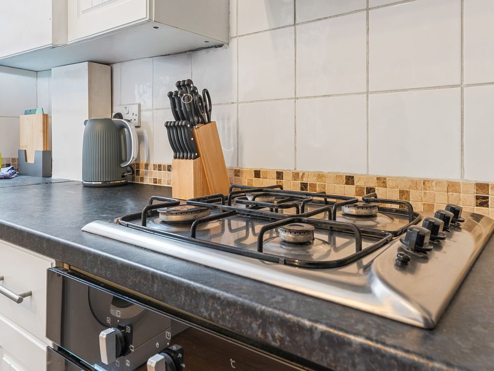 A kitchen with a gas stove, kettle, and knife block at The Gilder Birmingham City Apartment Birmingham
