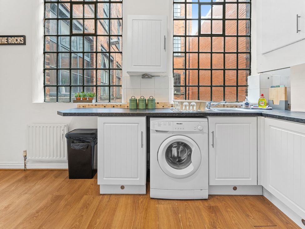 A kitchen with a washing machine and large window at The Gilder Birmingham City Apartment Birmingham