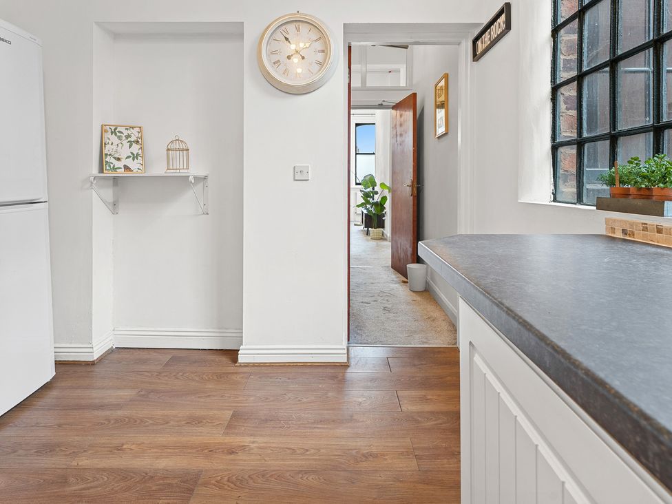 A kitchen with a refrigerator, wall clock, and a door at The Gilder Birmingham City Apartment in Birmingham