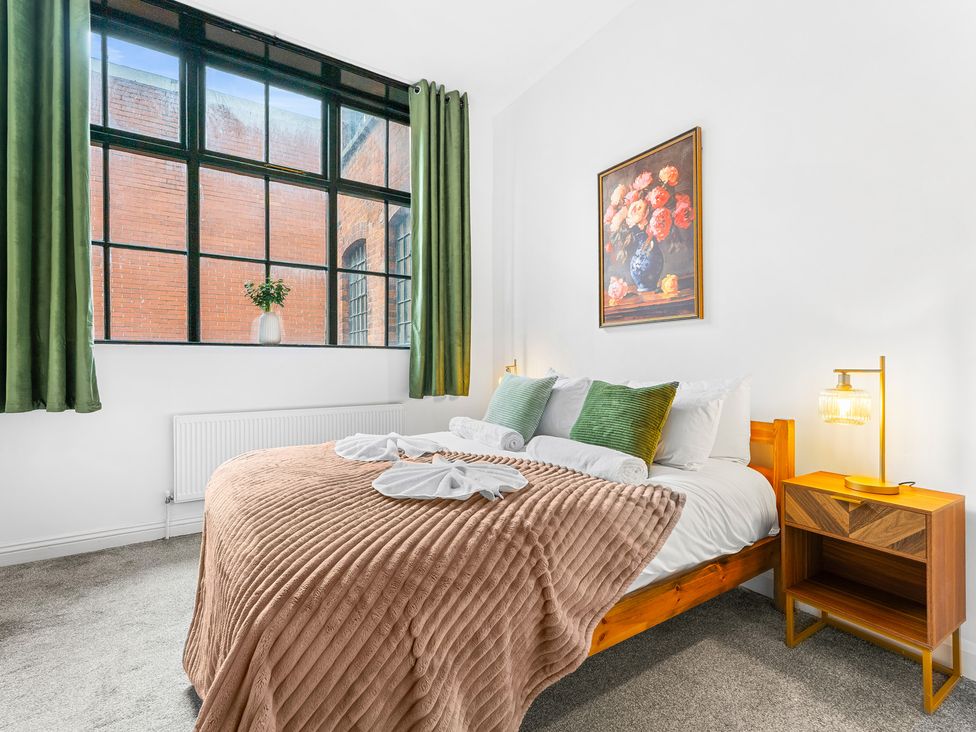 A bedroom with a bed, bedside table, and window at The Gilder Birmingham City Apartment in Birmingham