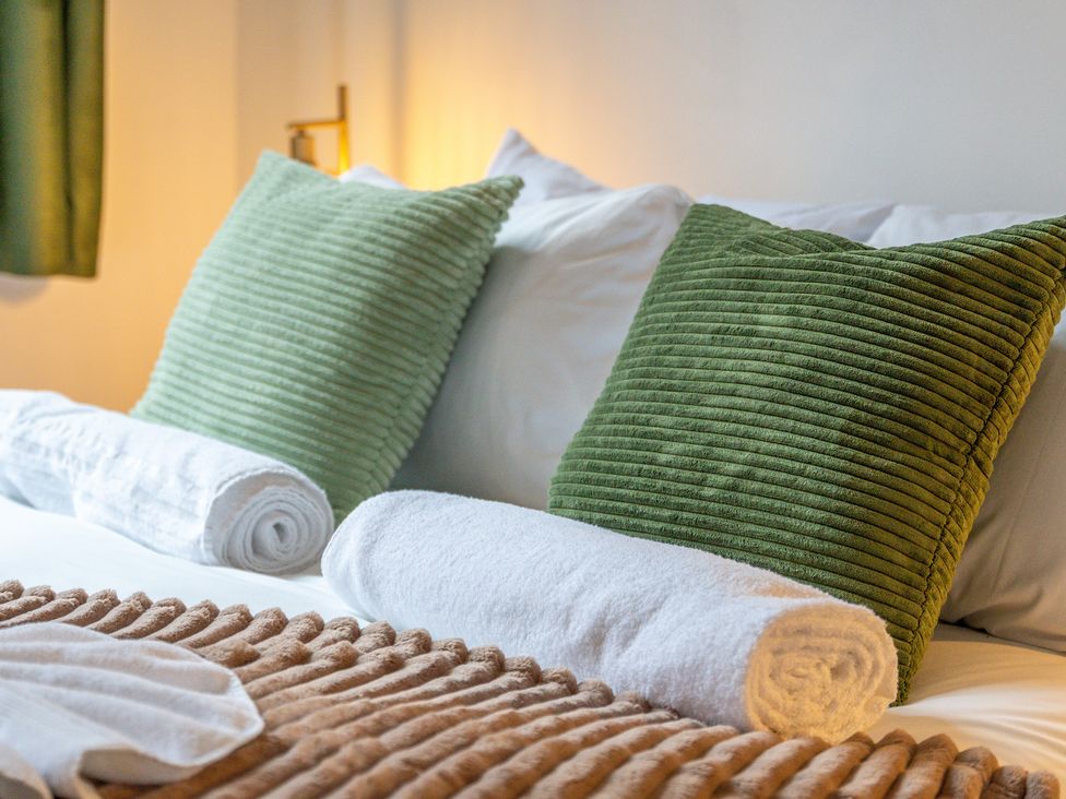 A bedroom with green pillows and rolled white towels at The Gilder Birmingham City Apartment in Birmingham