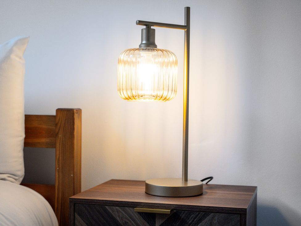 A lamp on a nightstand beside a bed at The Gilder Birmingham City Apartment Birmingham