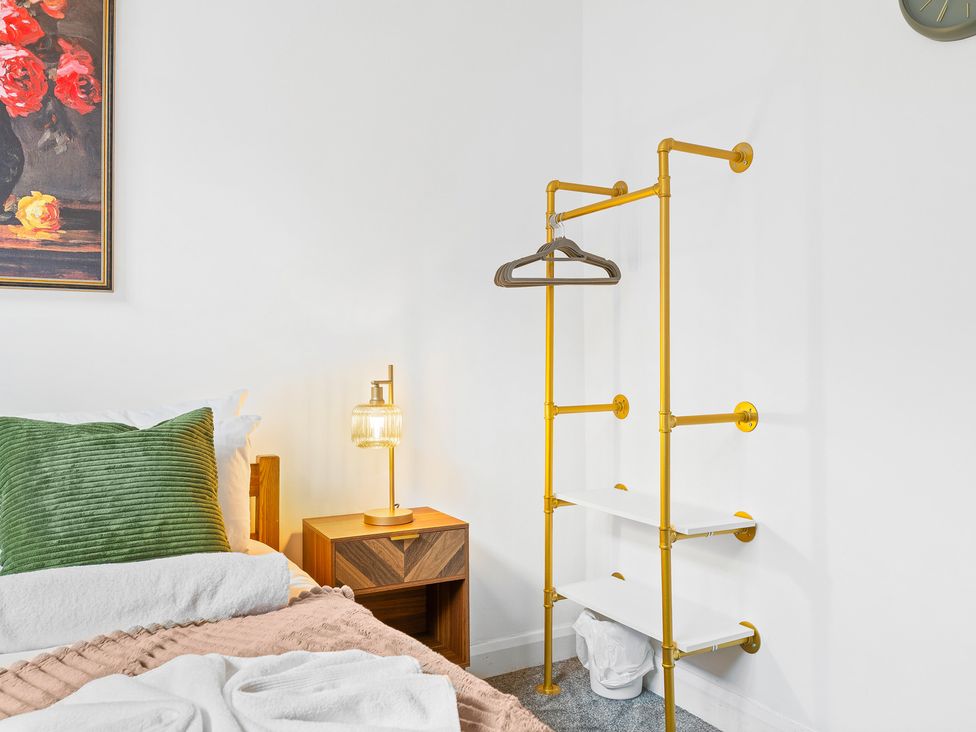 A bedroom with a bed, lamp, and clothes rack at The Gilder Birmingham City Apartment Birmingham